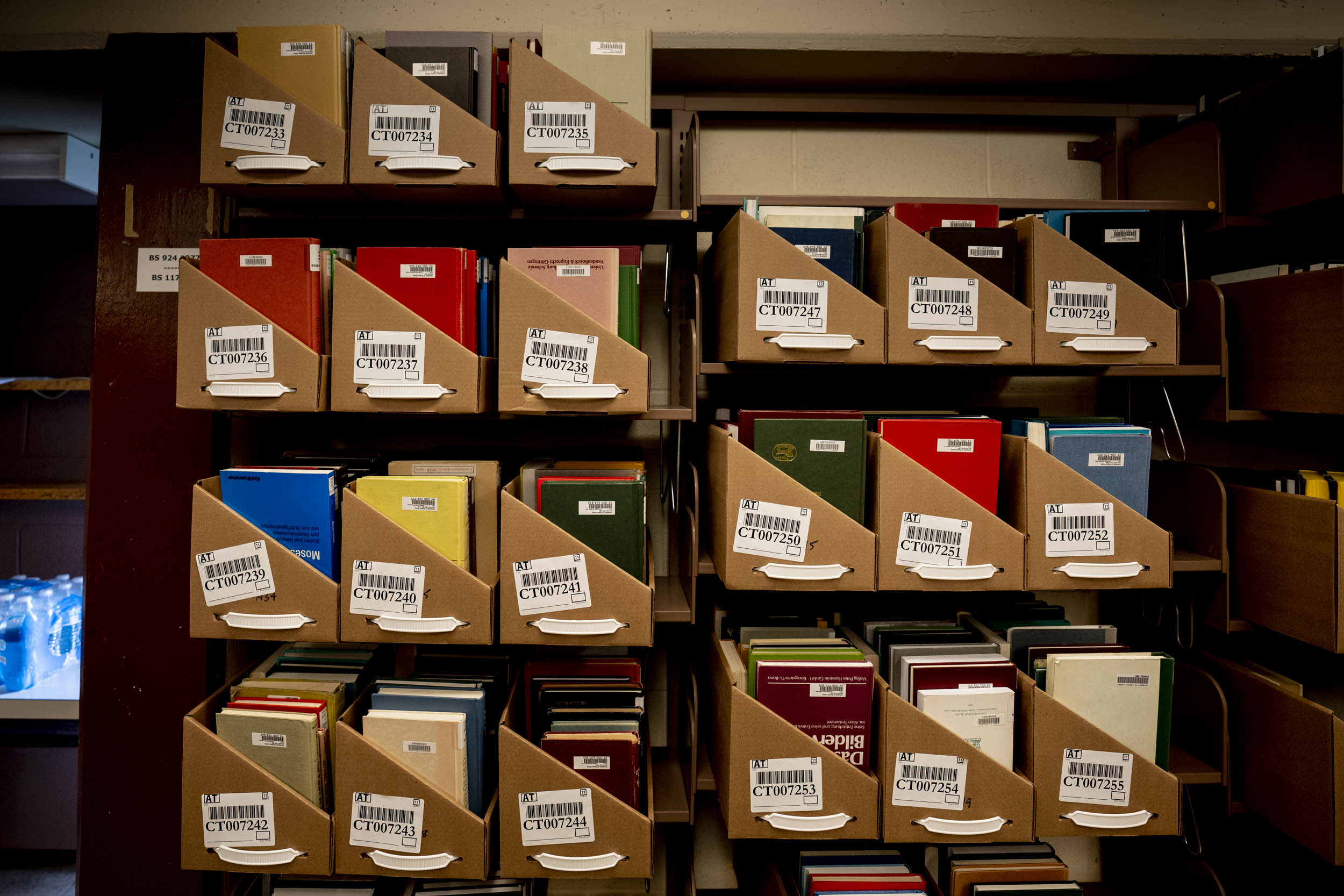 Alderman is being emptied in call number order, with books put into open cardboard boxes called “trays.” Multicolored books in Cardboard box shelves