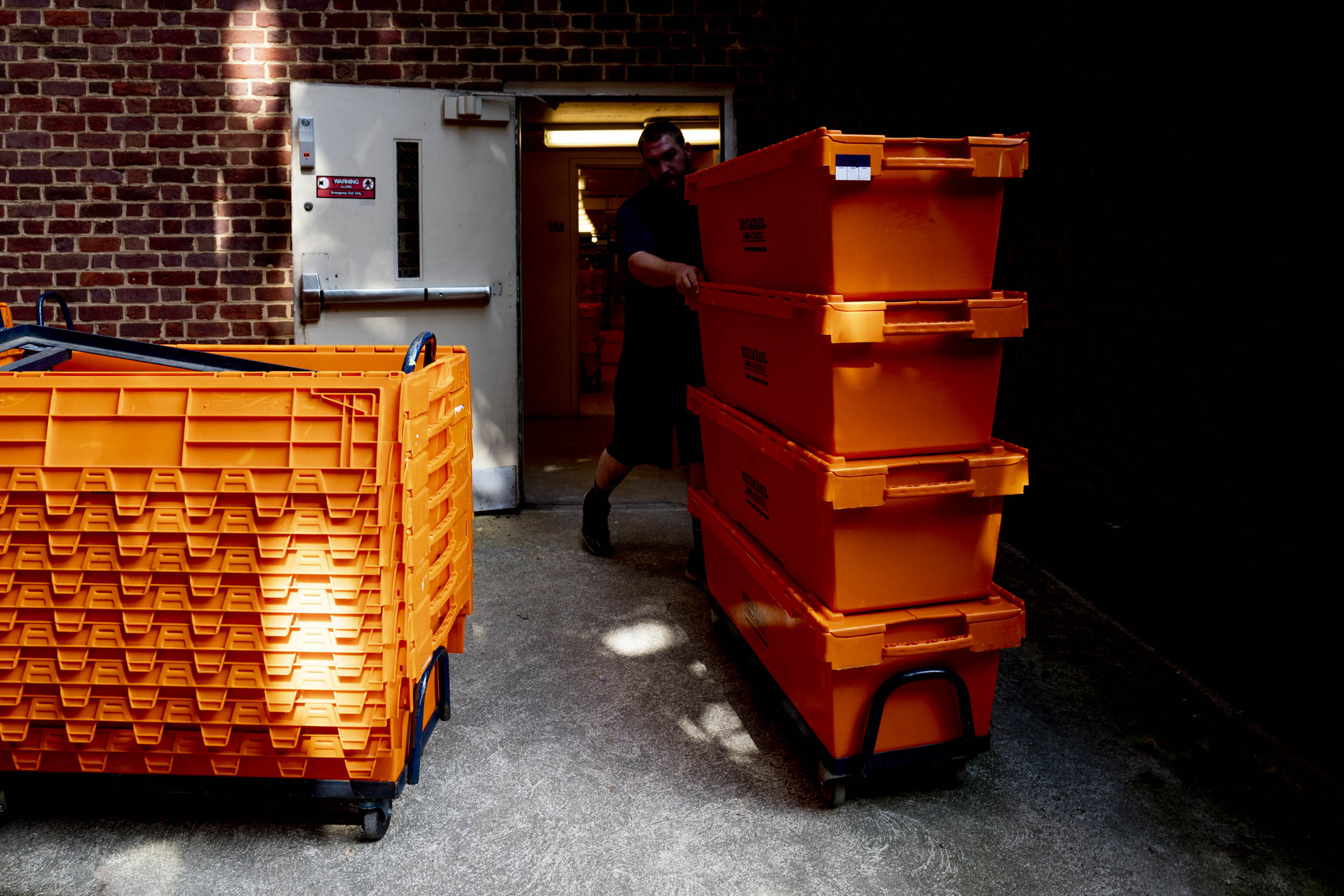 Moving books began after spring semester ended. Man moving bright orange boxes out of a building