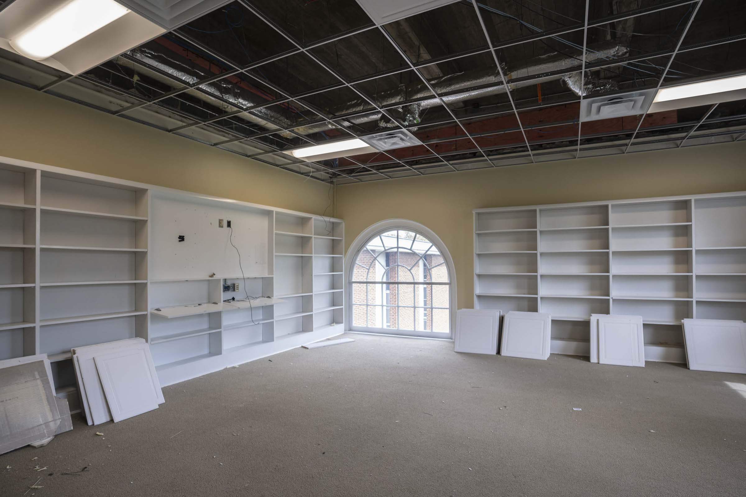 White wooden bookshelves line two walls 