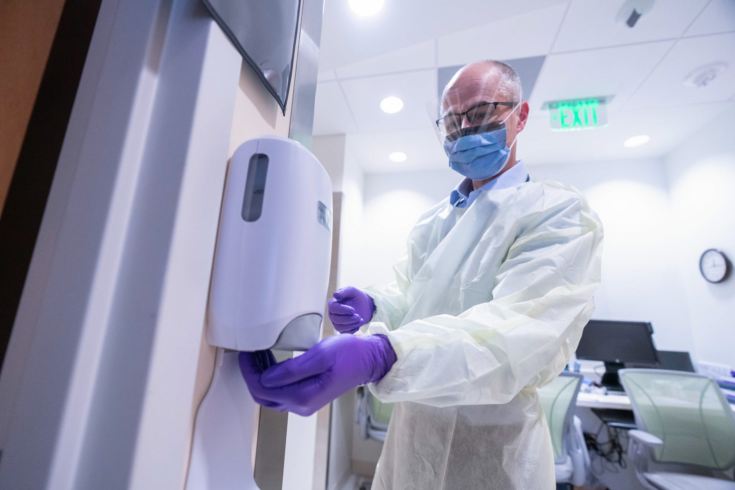 Medical professional getting hand sanitizer out of a dispenser