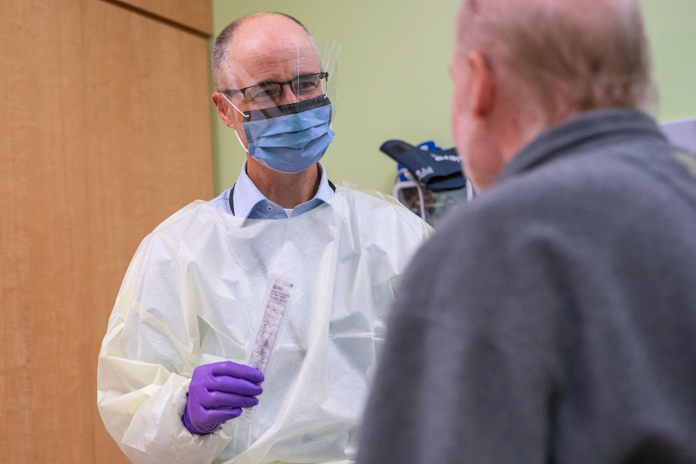 Medical Professional talking to a patient while holding a covid-19 swap in his hand