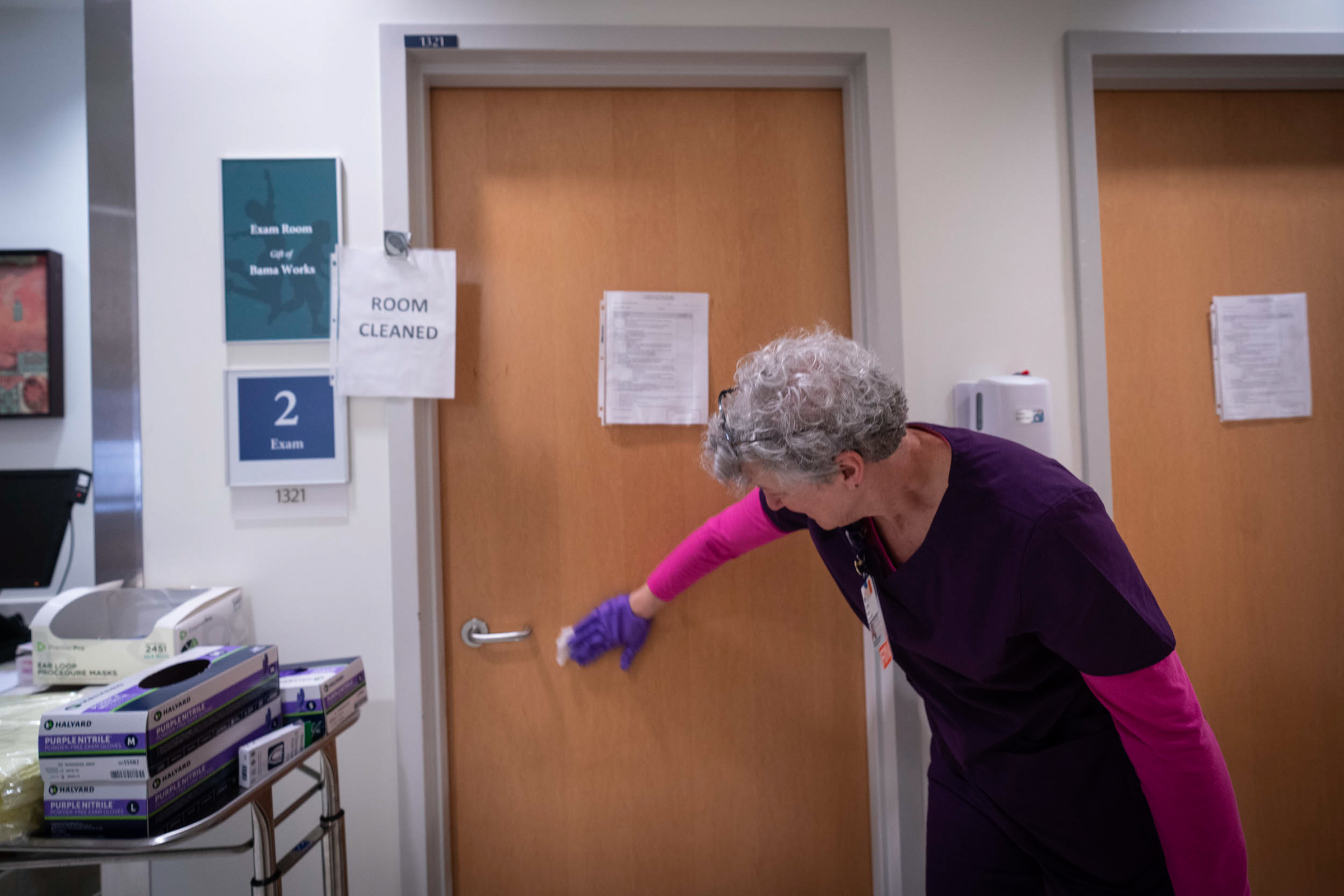 Staff member sanitizing an exam room door