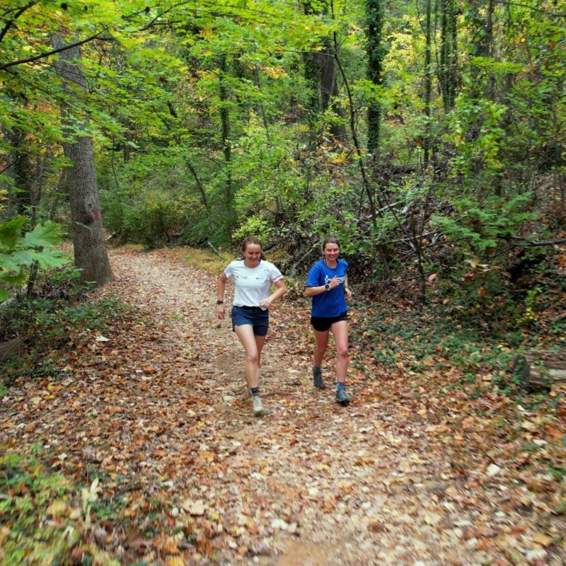 Emily Carder and Sophia Gibby running together on a wooded trail