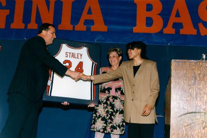 Dawn Staley on stage with Debbie Ryan accepting a framed basketball jersey